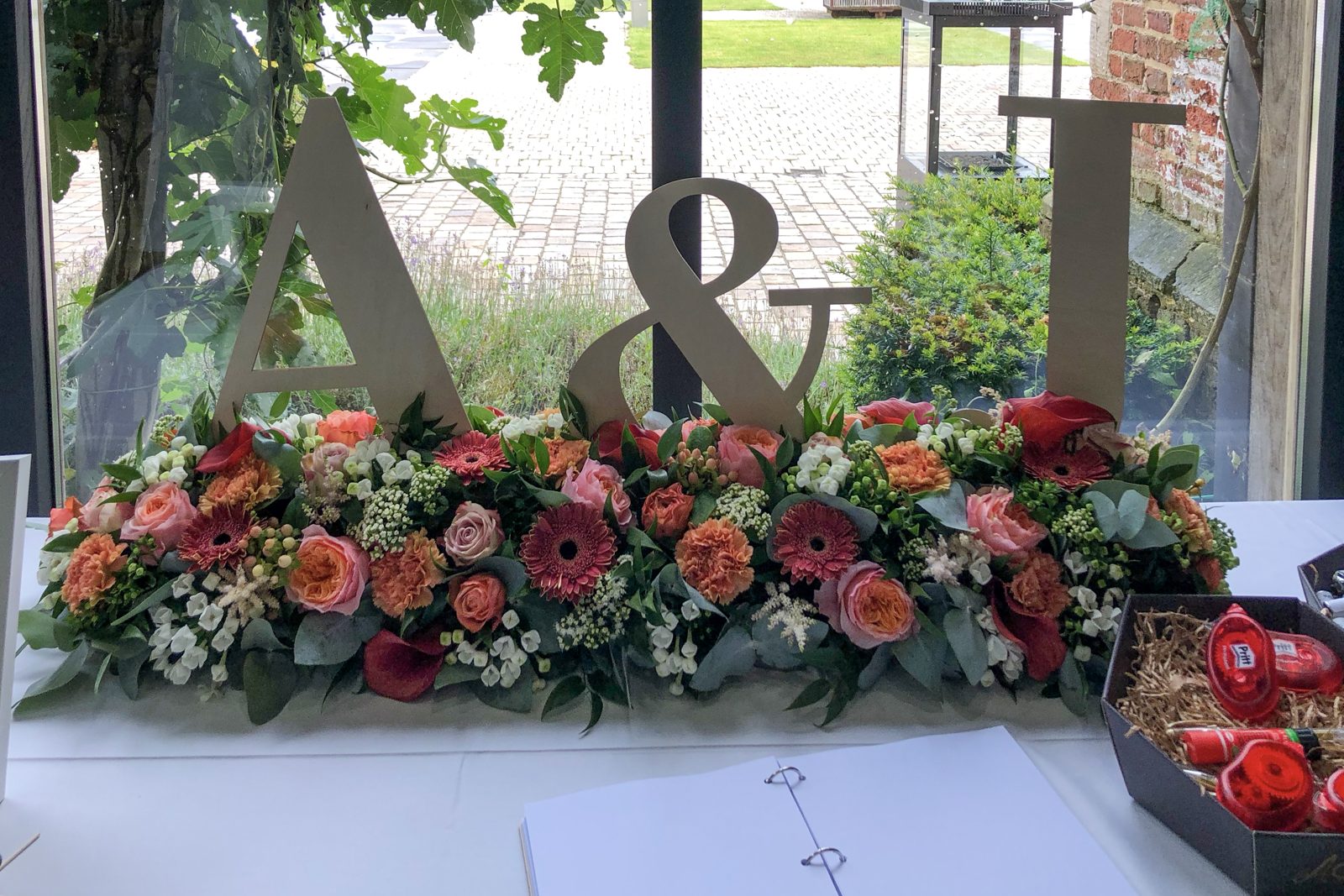 Bloemstuk in koraaltinten voor de eretafel met initialen