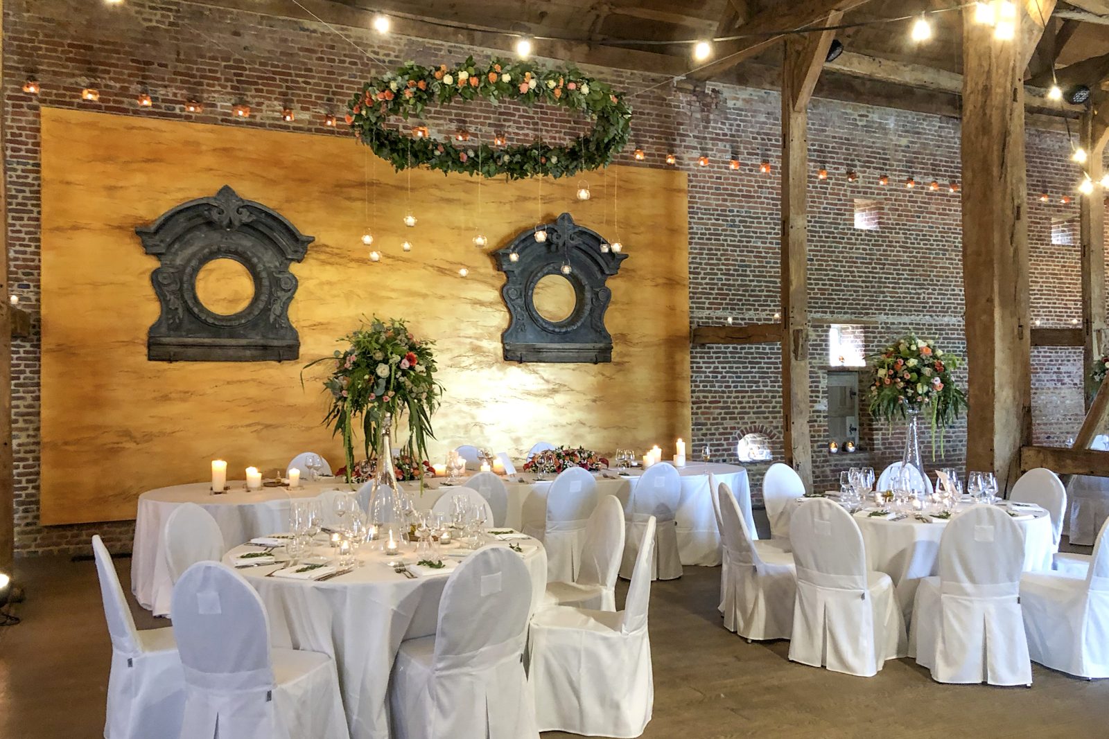 Zaal met bloemenkrans op de achterwand en gedekte tafels
