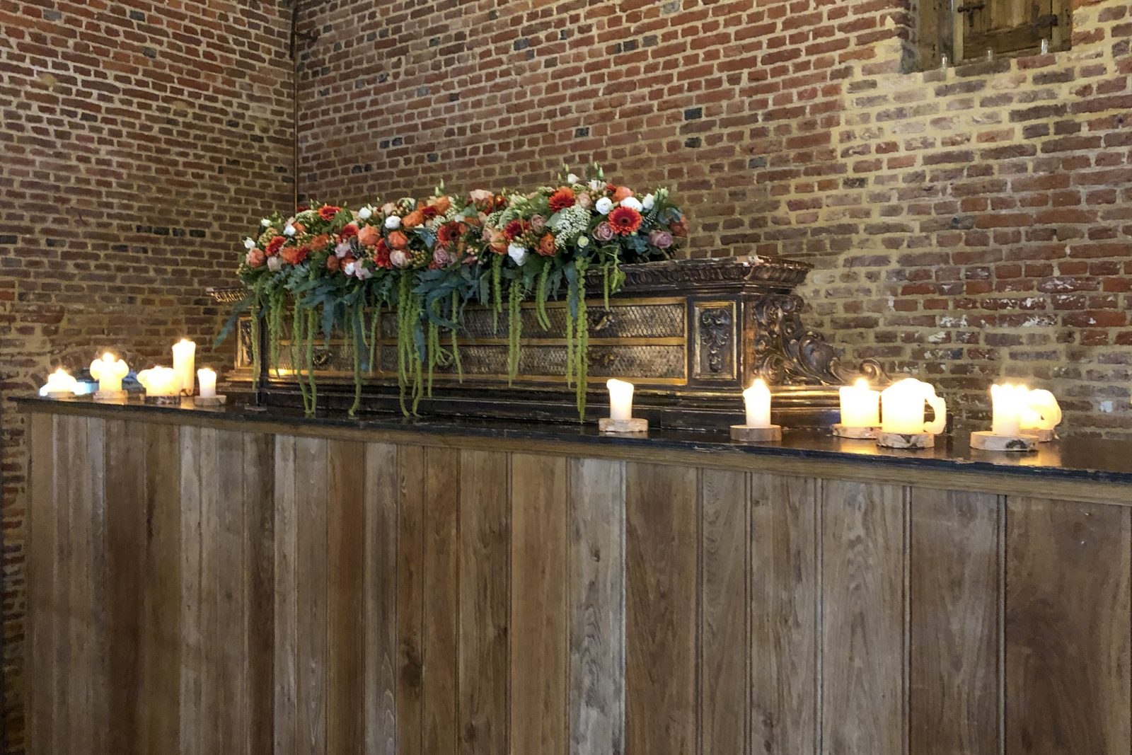 Bloemslinger over een houten toog met kaarslicht