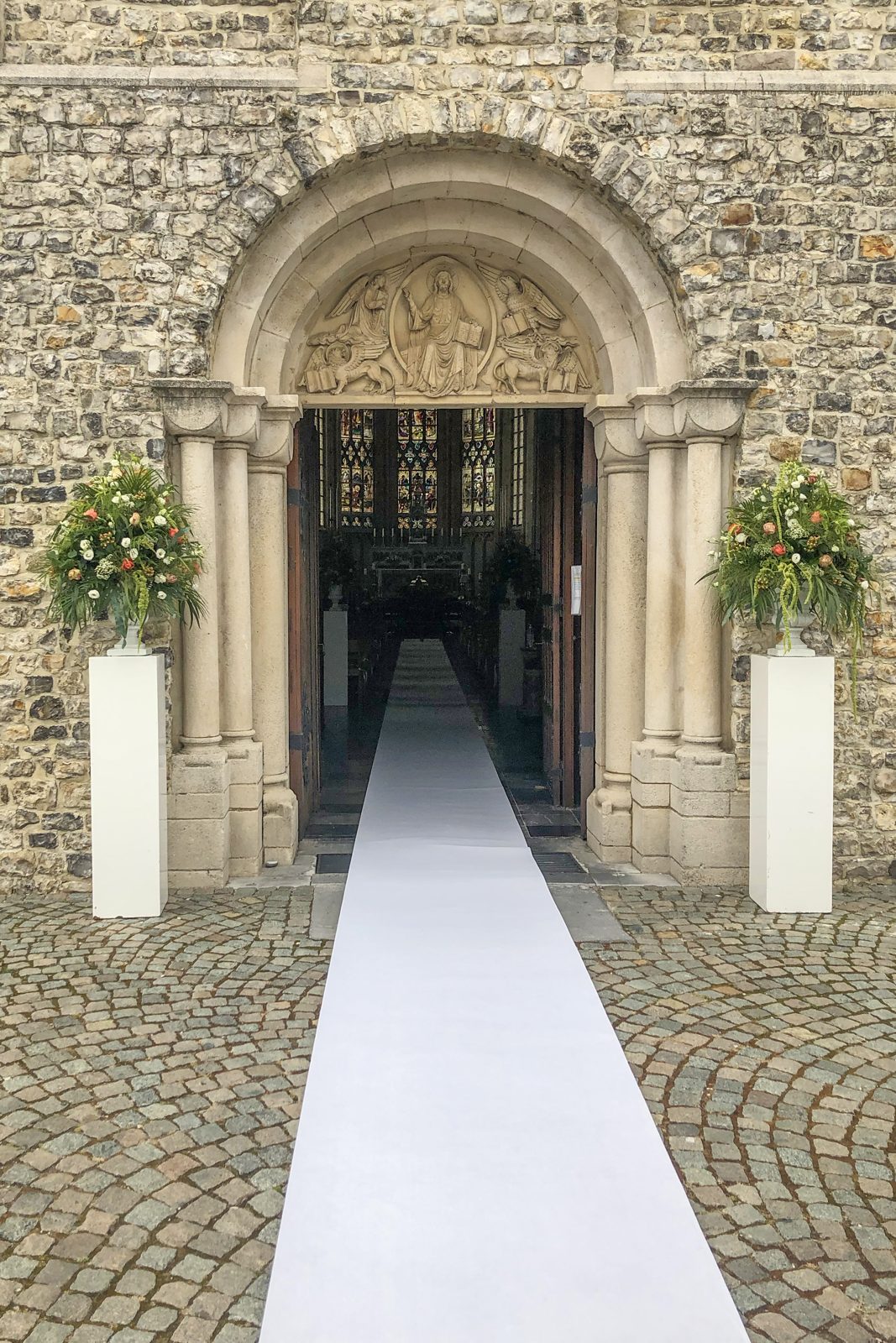 Bloemzuilen aan de kerkpoort met witte loper