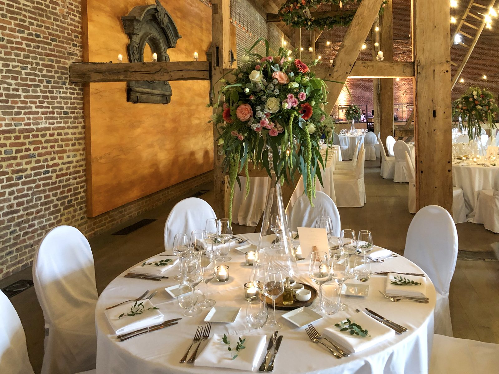 Hoge bloemstukken met rozen boven ronde feesttafels