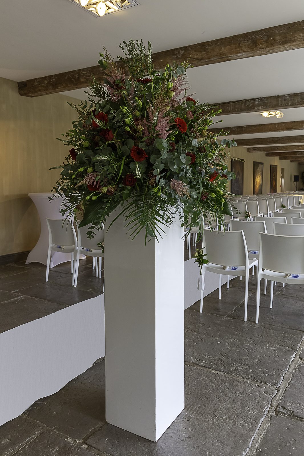 Groot losbloemig bloemstuk op een witte zuil